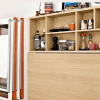 Small kitchen with shelf, refrigerator, and wall mounted table.