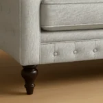 UK fabric sofa leg detail with button-tufted base and wooden feet