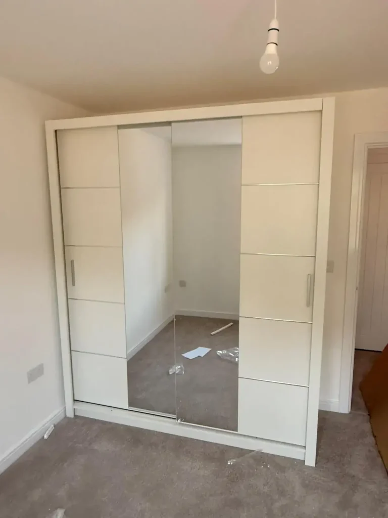 Oslo Sliding Mirror Wardrobe 180cm in White with three panel sliding doors and central mirror, installed in a bedroom. Delivered by Climax Furniture UK (1)
